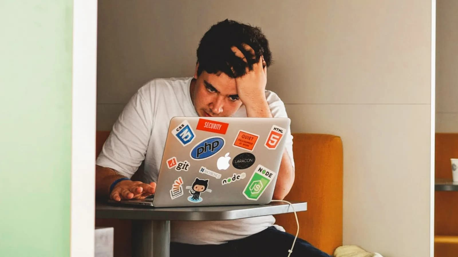 Hombre agobiado con la mano en el pelo frente a su laptop
